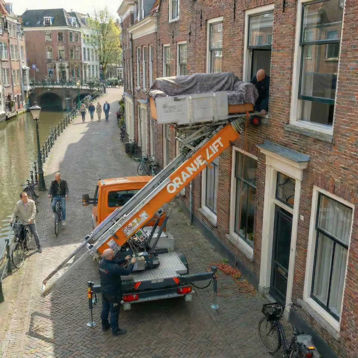 Ladderlift aan Amsterdamse gracht met bank op het platform